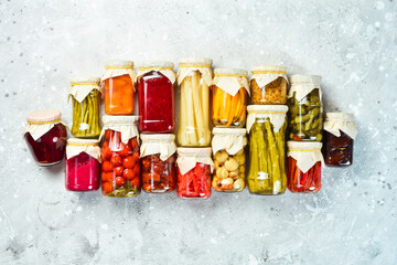 Jars with different vegetables on a stone background. Marinated vegetables. Food stocks in case of crisis. On a stone background. Top view.