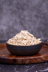 Oatmeal or Oat flakes on wooden background. Oatmeal in bowl. Close up