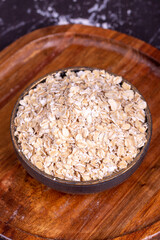 Oatmeal or Oat flakes on wooden background. Oatmeal in bowl. Close up