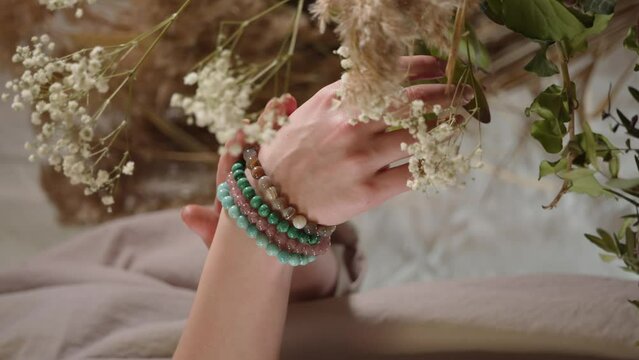 Women's hand with bracelets made of natural stones, colorful bracelets of beads. A vertical shot of women's hands in bracelets, handmade jewelry. 