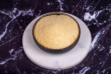 Dry organic semolina durum flour on dark background. Uncooked organic semolina in bowl