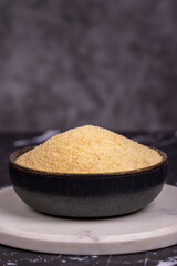 Dry organic semolina durum flour on dark background. Uncooked organic semolina in bowl. Close up