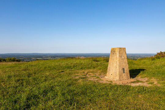 A concrete trig point on Ditchling Beacon with a blue sky overhead