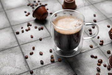 Cup of delicious espresso, pods and beans on grey grunge table