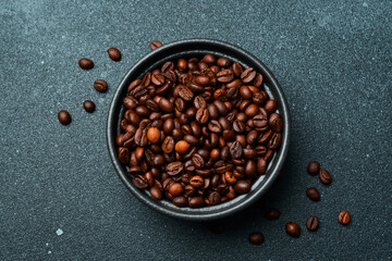 Roasted Arabica or Robusta coffee beans in a black bowl. Macro photo. Coffee background.