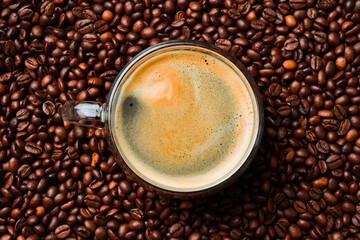A cup of freshly brewed hot espresso coffee. roasted coffee bean background, top view. Free space for text.