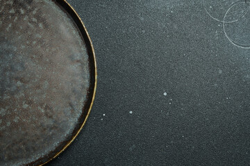Empty gray plate (ceramic) on a dark gray background. Free space for text. Top view.