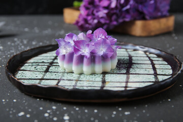 Plate of panna cotta with beautiful hydrangea flowers on black table