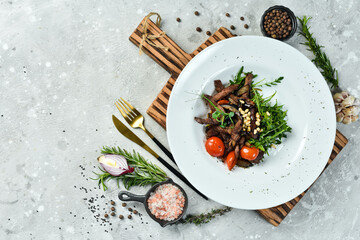 Fresh salad with veal: arugula, veal, pine nuts and eggplant. Healthy food. On a white plate....
