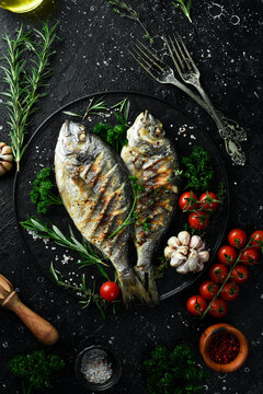 Grilled Dorado fish with spices and vegetables. On a black background. Photo for the menu.