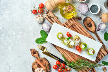 Fototapeta na wymiar Zucchini rolls with feta cheese. On a white plate. On a gray stone background. Restaurant menu.