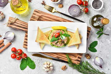 Fototapeta na wymiar Tartar. Salmon, avocado and onion tartare with bread toast. On a white plate. On a gray stone background. Restaurant menu.
