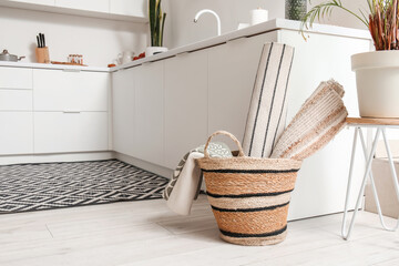 Fototapeta na wymiar Basket with different rugs in interior of modern kitchen