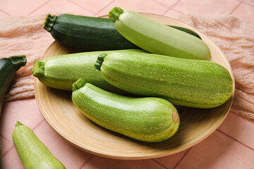 Plate with fresh zucchini on beige tile background