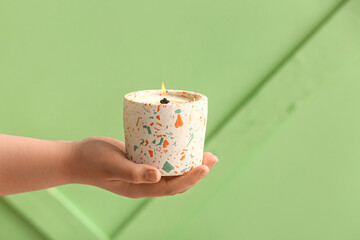 Woman holding burning candle on green background