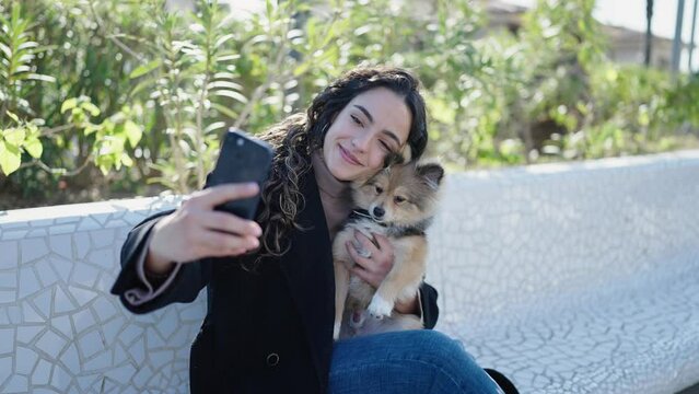 Young hispanic woman with dog smiling confident make selfie by smartphone at park