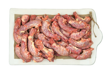 Chicken necks on a ceramic board isolated on white background. Top view.