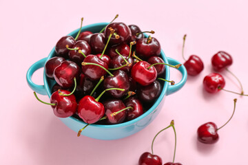 Bowl with sweet cherries on pink background