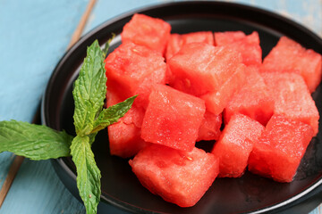 Plate with pieces of fresh watermelon and mint on blue wooden background