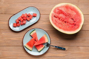 Half of fresh watermelon and plates with pieces on wooden background