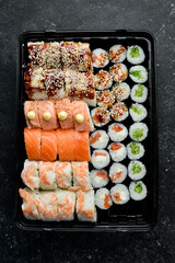 Sushi and rolls. Chinese food set. Takeout, food delivery. On a black stone background.