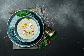 Homemade cream soup of fresh mushrooms and cheese, in a bowl. On a dark background, close-up.