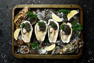 A plate of Fresh oysters with black sturgeon caviar lemon and ice. Restaurant delicacy. oysters...