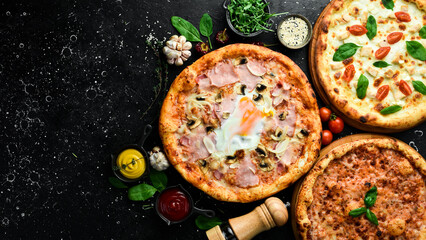 Pizza background. Set of delicious pizza and ingredients on black stone background. Top view.