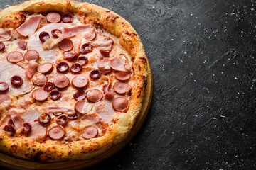 Pizza with sausages, bacon and cheese. classic pizza On a black stone background. Top view.