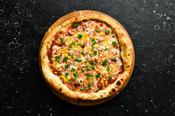 Pizza with tuna, corn and cheese. classic pizza On a black stone background. Top view.