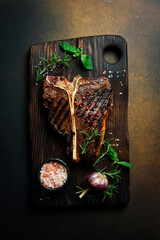 The T-bone or porterhouse steak of beef cut from the short loin. On a dark slate background.