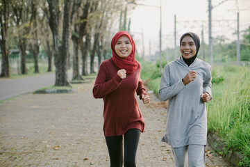 two asian muslim women running and exercising outdoors