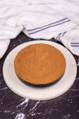 Cinnamon powder on dark background. Powdered dried cinnamon in bowl. Spice concept