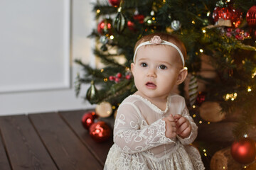 Cute little baby sits on floor. Christmas portrait, cozy style.