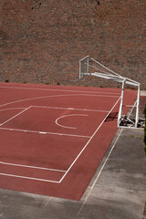 Basketball playground in front of the high-rise brick wall.