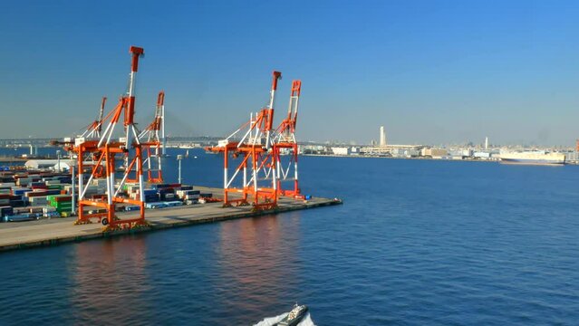 Yokohama, Japan - 01.07.2023 - Gantry cranes of Yokohama container terminal in stand by position waiting for next ship and small boat passing in the water