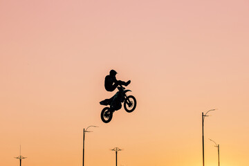 FMX rider performs dangerous stunts at sunset. Motocross.