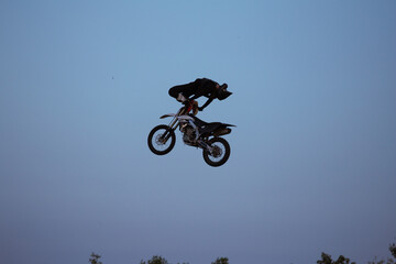 Fototapeta na wymiar FMX rider performs dangerous stunts at sunset. Motocross.