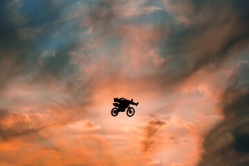 FMX rider performs dangerous stunts at sunset. Motocross.