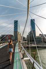 A woman gracefully crossing a modern bridge in Bilbao, the city's architectural marvel blending elegance and functionality.