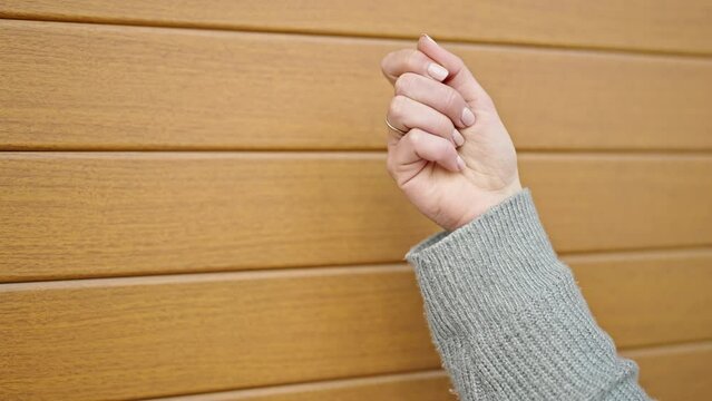 Young blonde woman knock the door over isolated wooden background