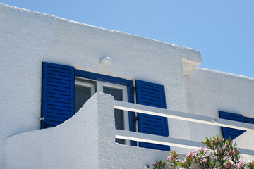 A white washed house with blue window shutters and a balcony in Ios Greece - obrazy, fototapety, plakaty