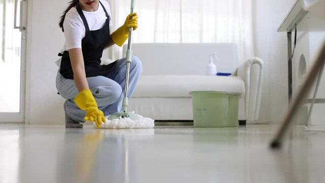 Woman using a mop to wipe and clean the floor in the house.