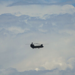 Fototapeta na wymiar Transport helicopter flying between large clouds