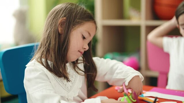 Adorable girls student cutting paper drawing on paper at kindergarten