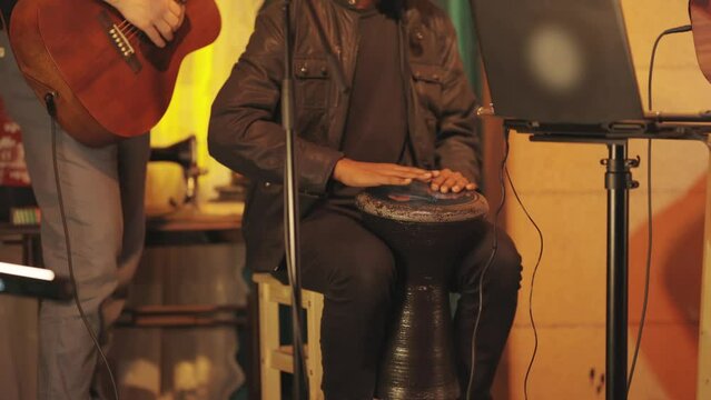 A musical group performs on stage in a bar - a man plays a bata instrument