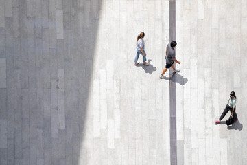 Obraz na płótnie Canvas people walk on across the pedestrian concrete landscape in the city street (Aerial top view)