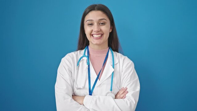 Young beautiful hispanic woman doctor standing with arms crossed gesture saying yes with head over isolated blue background
