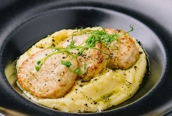 mashed potatoes with meat cutlets on black plate