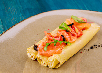 Delicious thin pancakes with salmon and sour cream on plate